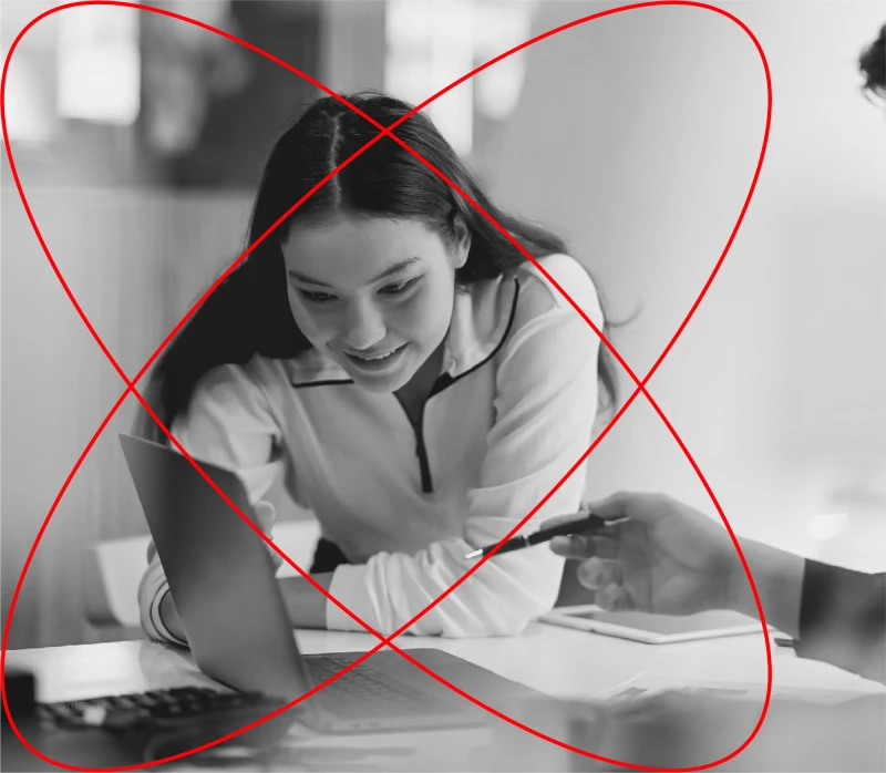 Black and white image of a woman leaning into computer screen, with two red circles.